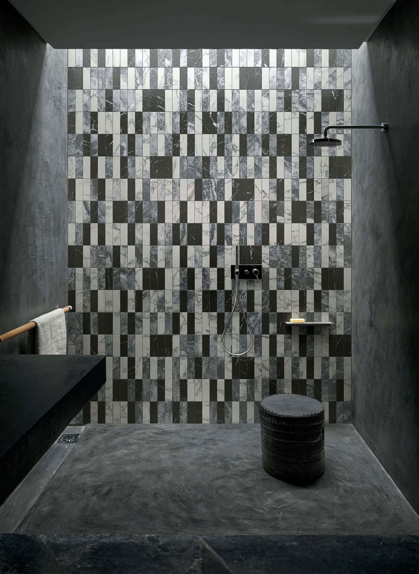 Zona de duche de casa de banho minimalista em tons de preto. Parede em mármore mate com padrão de retângulos em preto, cinza e branco. Acabamento mate e sem reflexo. Bisazza, coleção Marmo em parceria com Studio KO